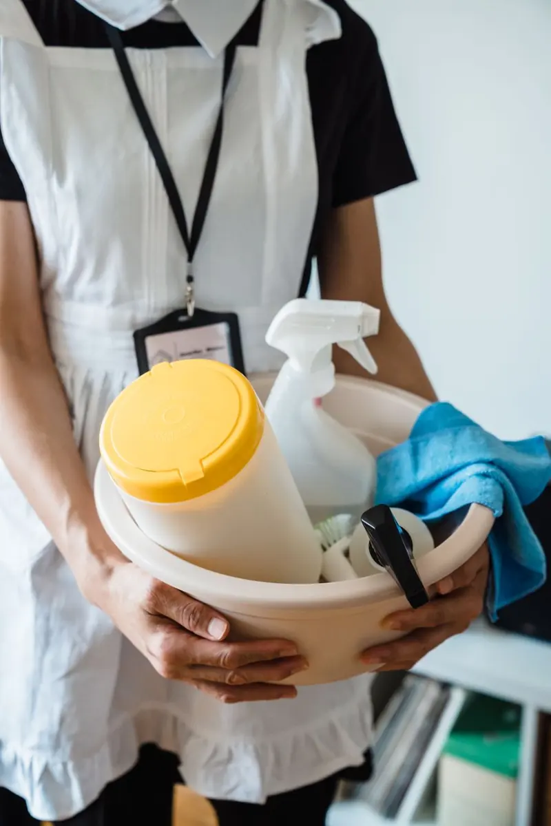 Person holding a basin of cleaning supplies