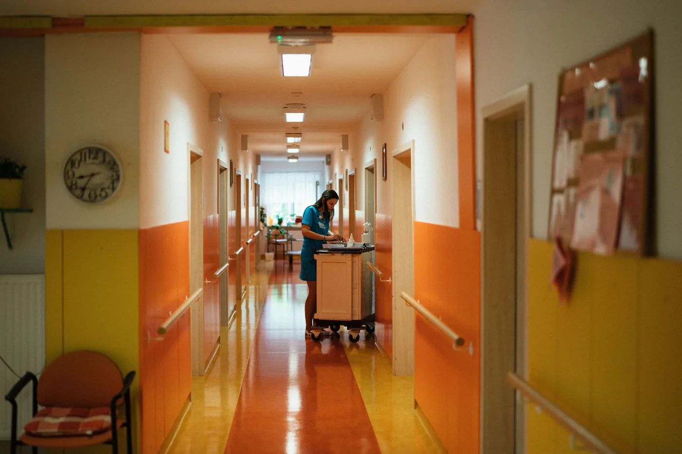 Staff member with a service cart in a bright aged care facility corridor