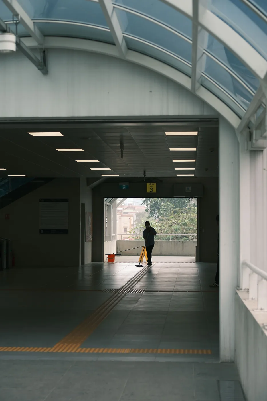Cleaner mopping a bright transit passageway