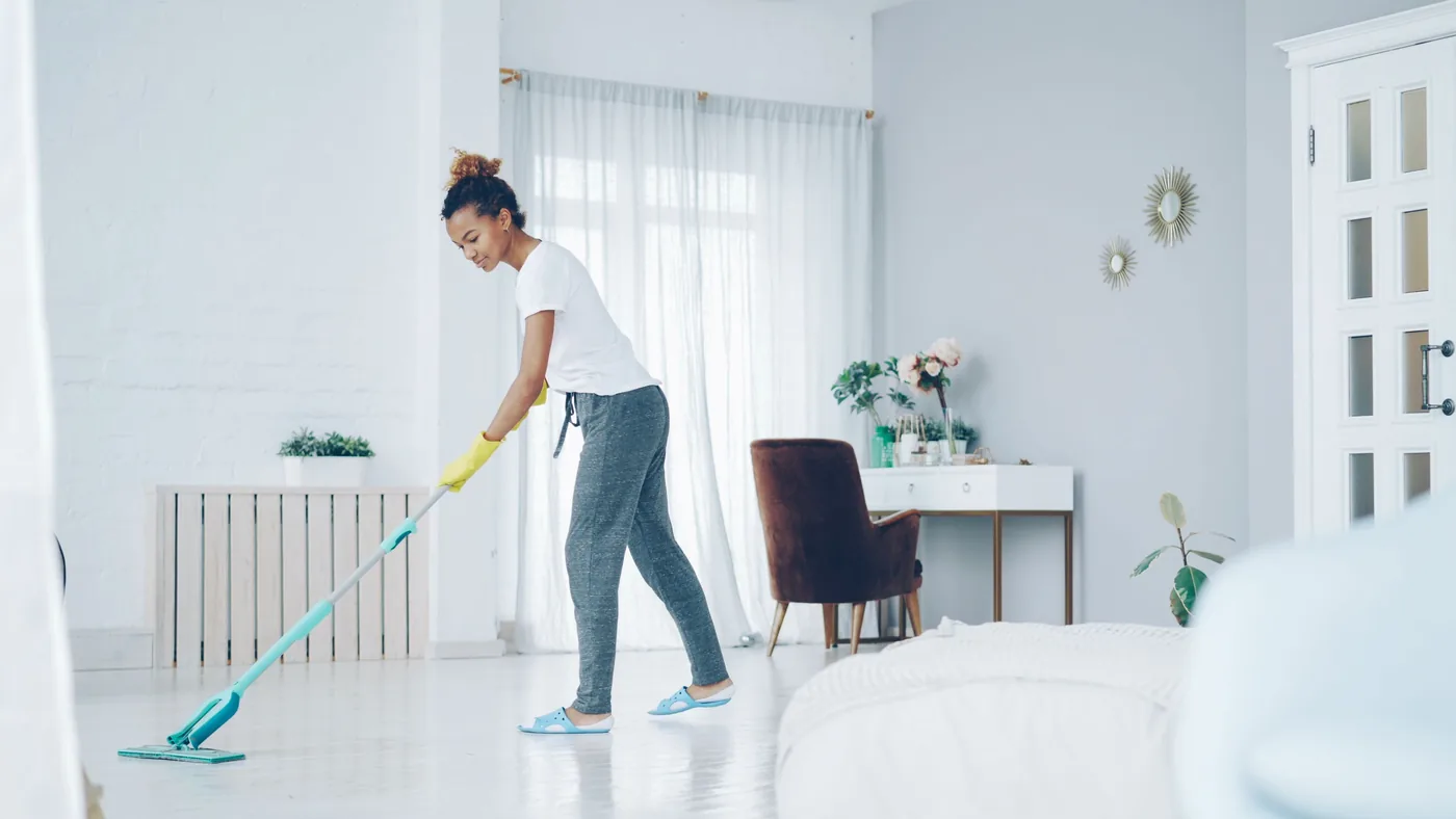 Cleaner mopping a bright, near-empty room during a move-in or move-out clean