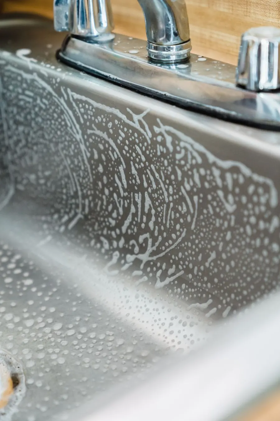 Cleaner wiping down a kitchen sink and surfaces