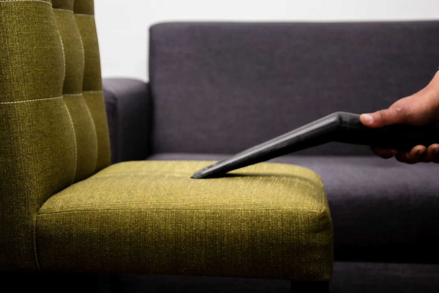 Cleaner using a handheld vacuum attachment on sofa upholstery